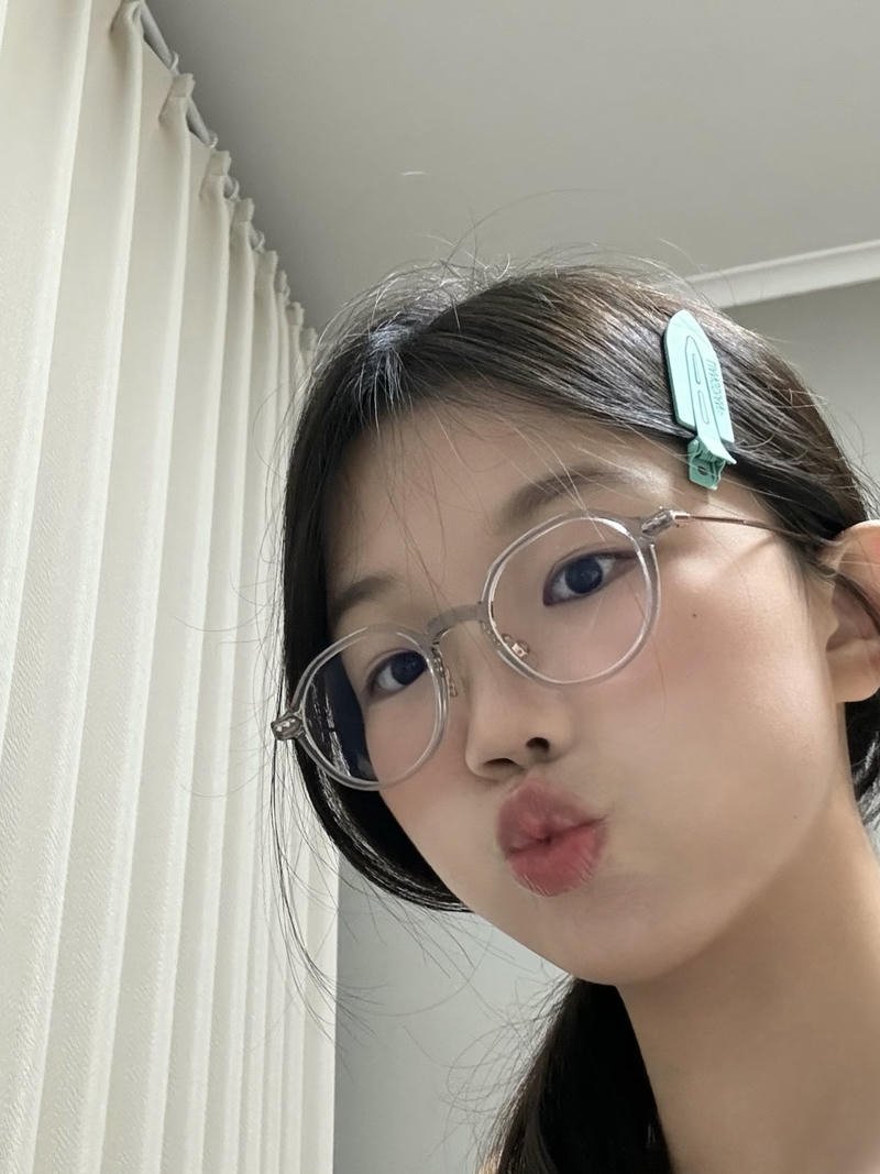 Gái xinh đeo kính đứng trước nền tường sáng